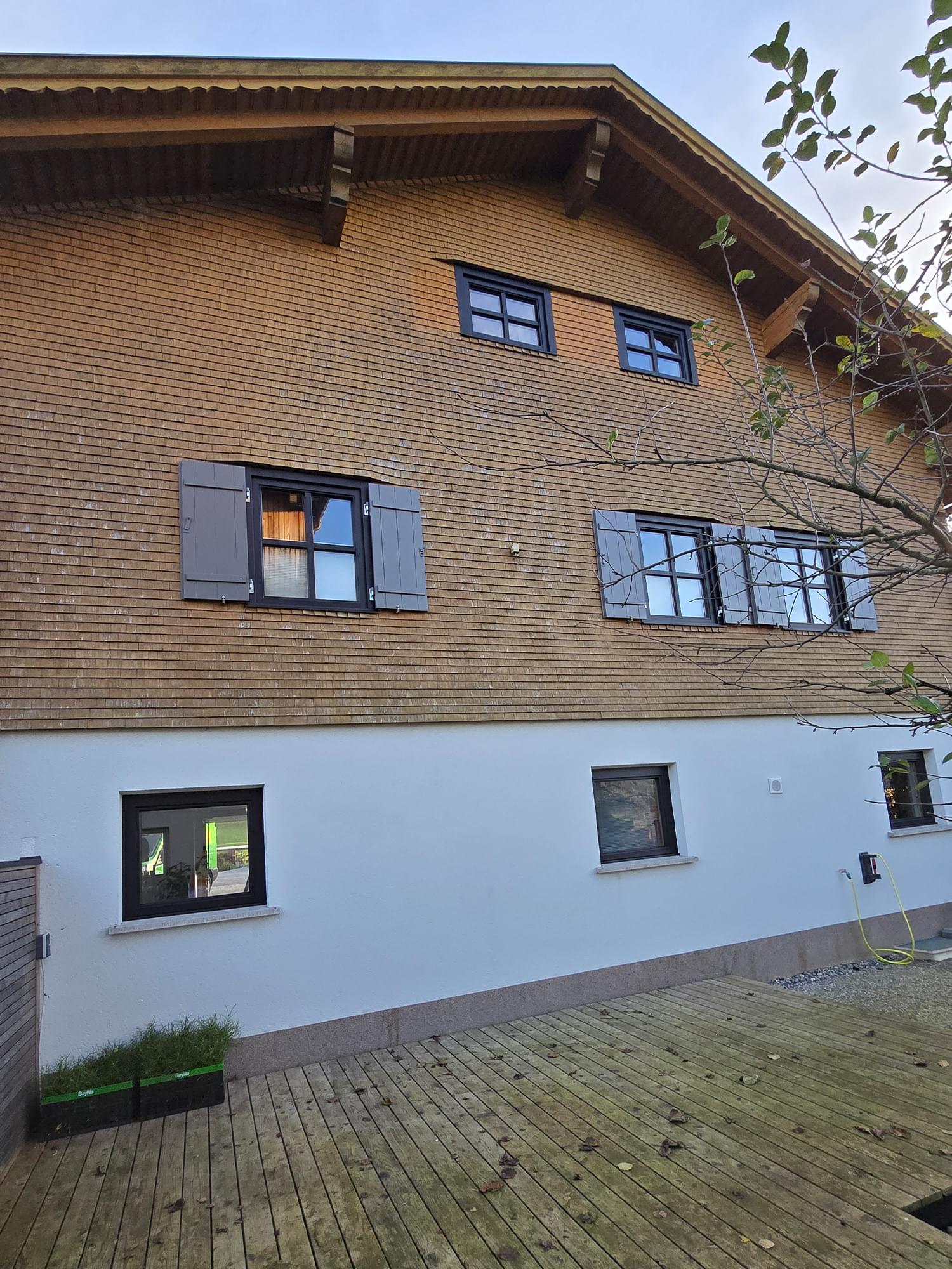 Schwarze Aluminium-Schale auf renovierten Holzfenstern in traditioneller Holzfassade