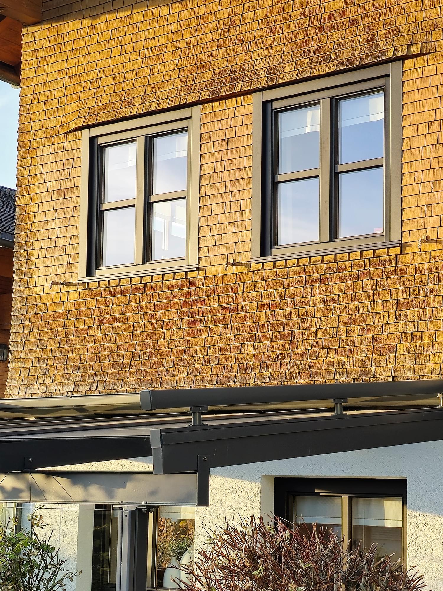 Schwarze Aluminium-Schale auf renovierten Holzfenstern in traditioneller Holzfassade