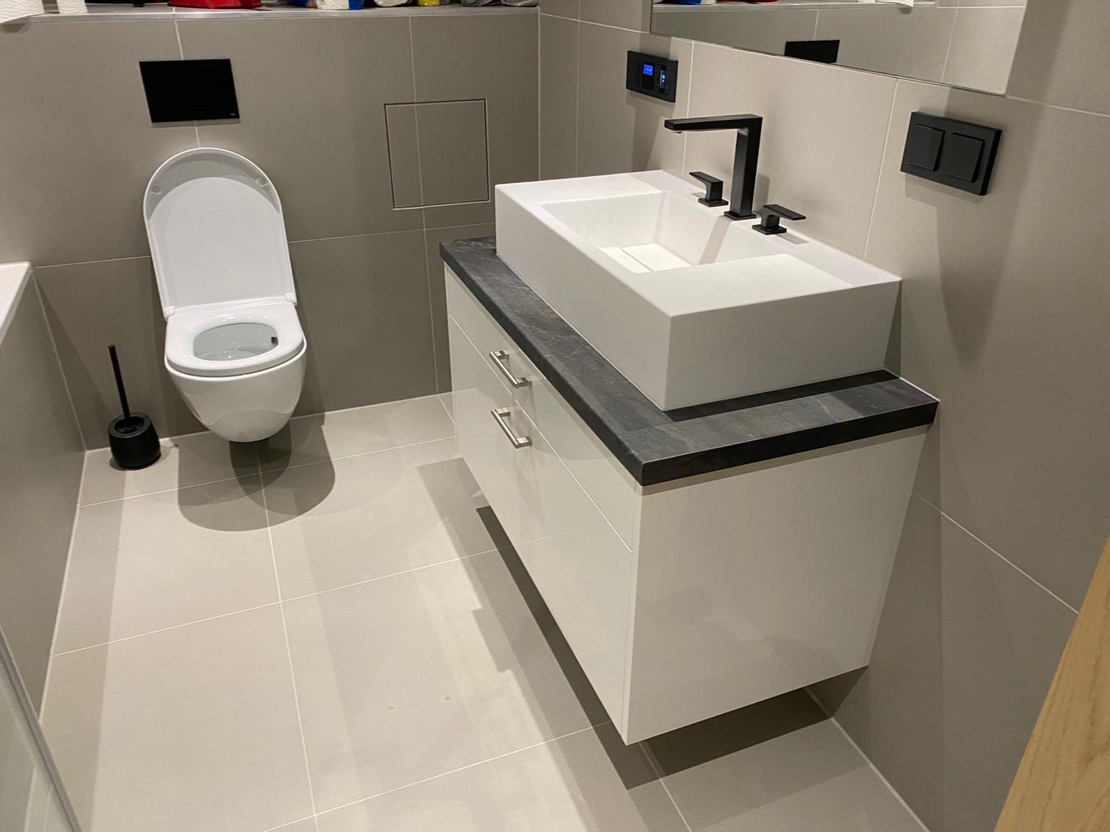 Badezimmer modern in weiß, Arbeitsplatte mit Steinoptik, modernes aufgesetztes Waschbecken mit schwarzen Armaturen